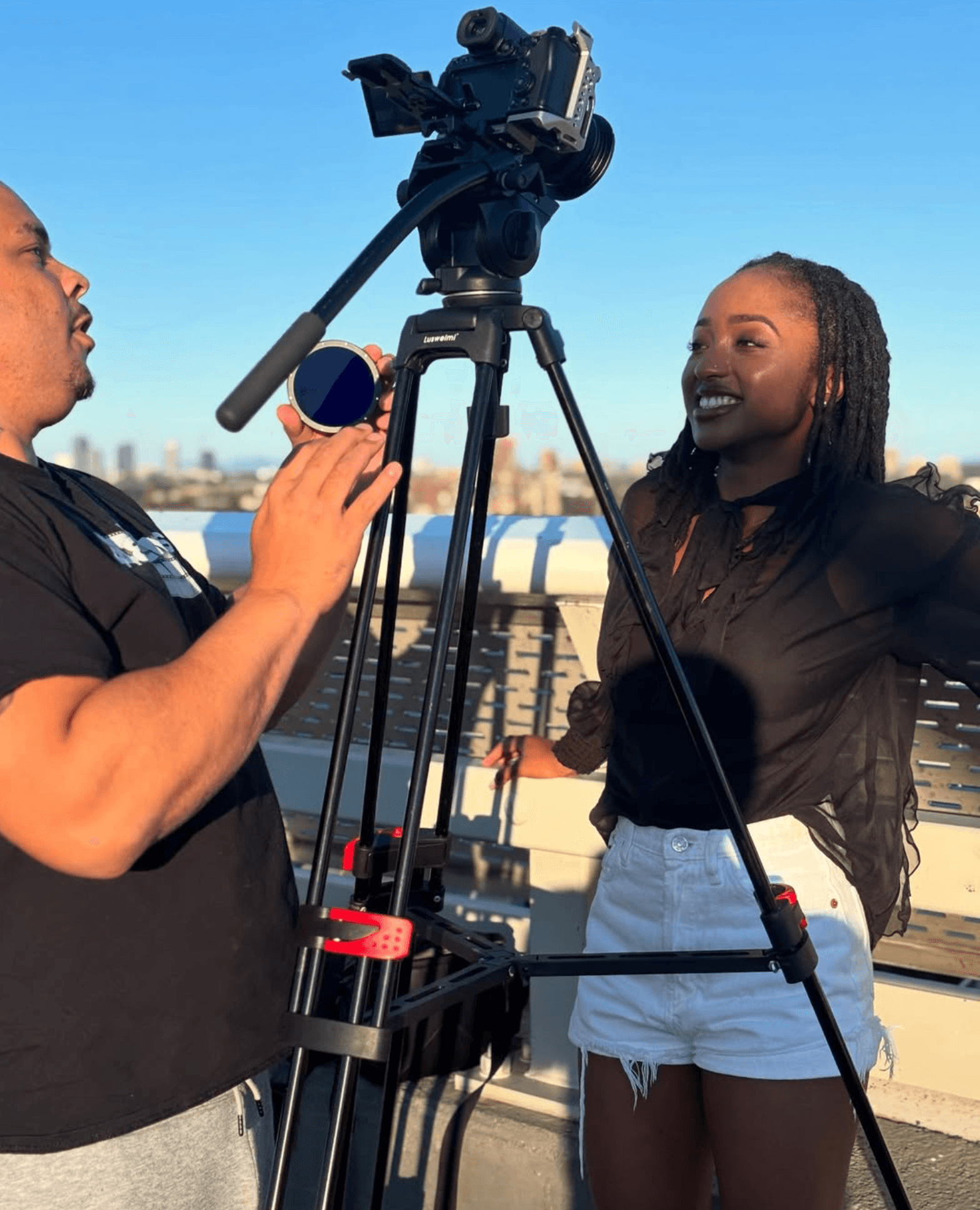 Lioness Productions artist development shoot with filmmaker adjusting a cinema camera while talent is framed on the right.